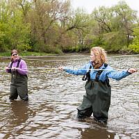 三个学生在他们的水文地质学课程的实地研究中测试了一条溪流的水流运动.